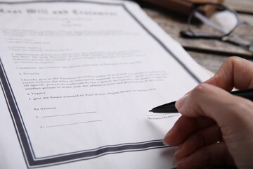 Woman signing last will and testament at table, closeup - obrazy, fototapety, plakaty