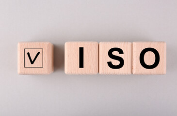 International Organization for Standardization. Wooden cubes with check mark and abbreviation ISO on light grey background, flat lay