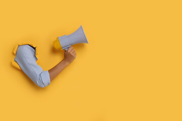 Special promotion. Woman holding megaphone through hole in orange paper, closeup. Space for text