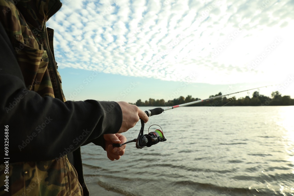 Wall mural Fisherman with rod fishing at riverside, closeup