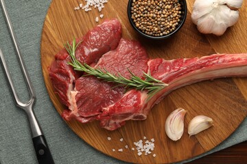 Raw ribeye steak, spices and fork on table, flat lay