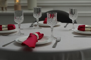 Color accent table setting. Glasses, plates, cutlery and pink napkins on table indoors