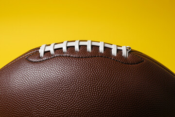American football ball on yellow background, closeup