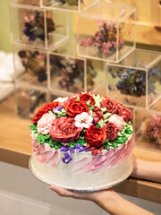 hand holding a cake with flower decorations on it