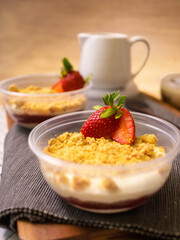 Chocolate vanilla pudding with biscuit topping and strawberries on the table