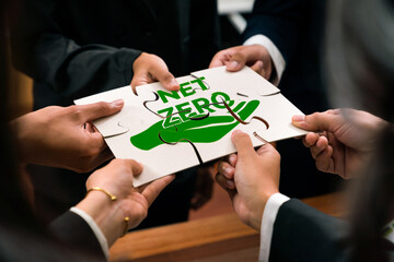 Cohesive group of business people forming jigsaw puzzle pieces in net zero icon symbol as eco...
