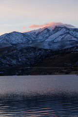 pink clouds over utah mountain by lake in winter at sunset