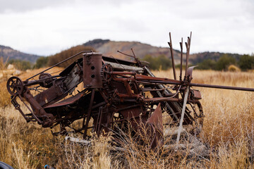 broken down old farm equipment sitting in a grassy field