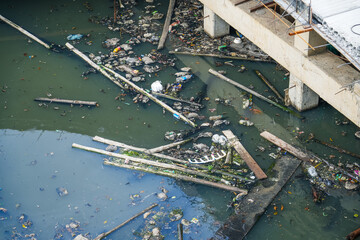 Polluted city canal with large construction debris and small household waste.