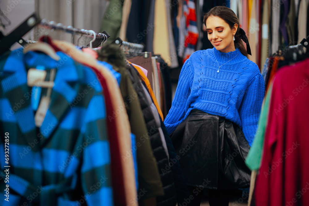 Wall mural Trendy Woman Wearing a Blue Sweater Buying Warm Clothes. Elegant chic fashionista looking for new clothes in a store
