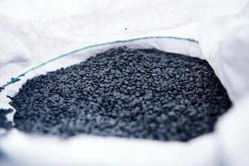 Black granules made of recycled waste plastic in open sack