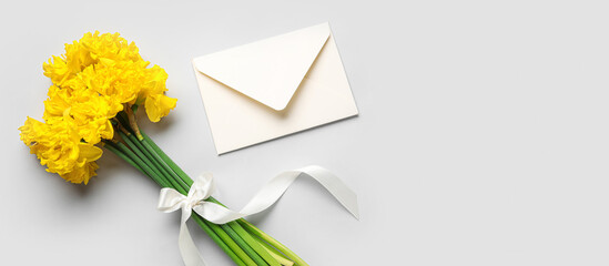 Bouquet of beautiful narcissus flowers and envelope on light background with space for text, top view - obrazy, fototapety, plakaty