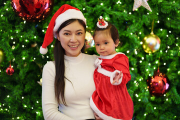 happy mother with daughter in santa dress and the christmas tree. happy new year eve