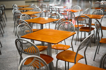 Wooden tables and chairs at large empty foodcourt in mall