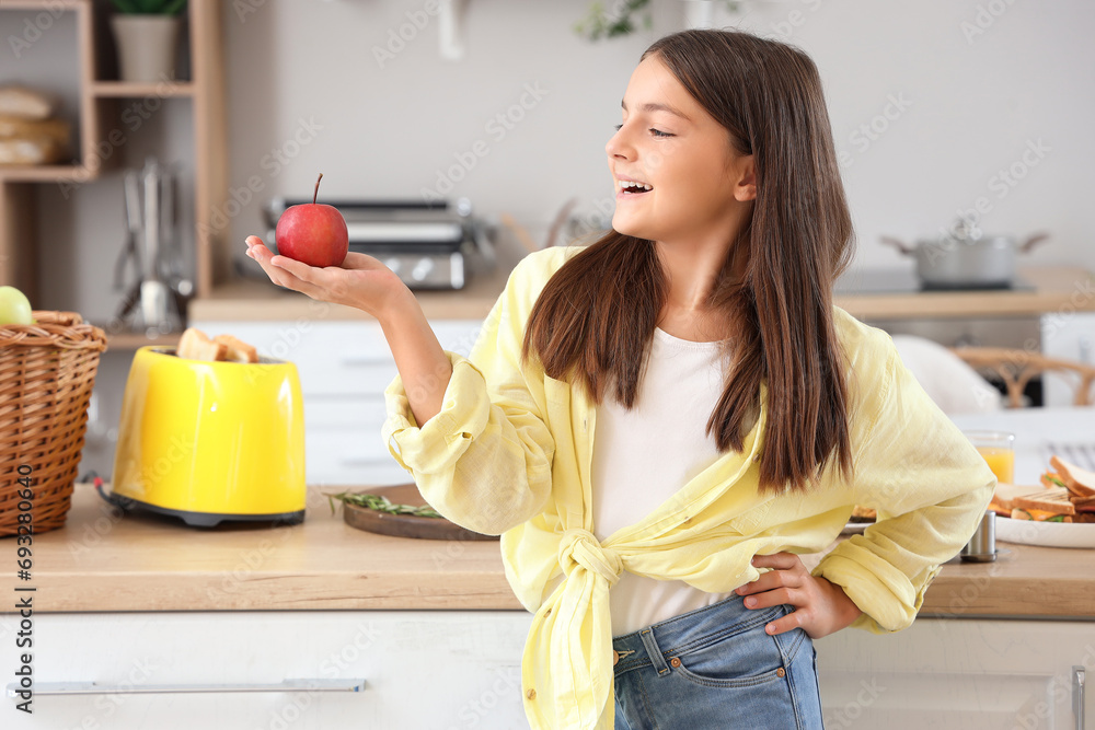 Sticker Cute little girl with fresh apple in kitchen