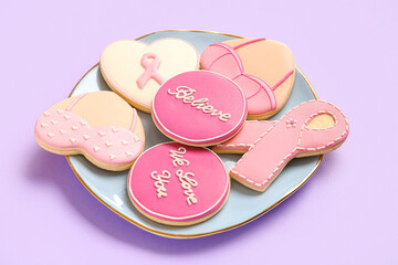 Plate with pink cookies on lilac background. Breast cancer awareness concept