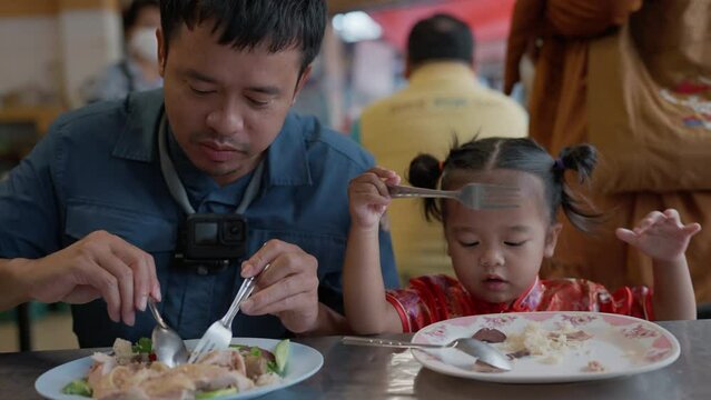Dad with little daughter eat chicken rice in Yaowarat street food Bangkok Thailand