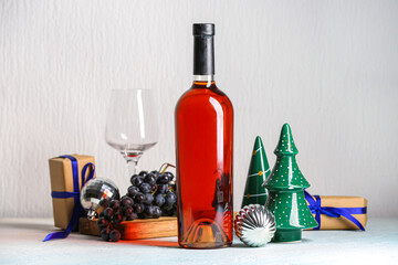 Bottle of wine with glass and Christmas decorations on white background