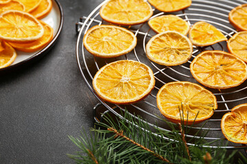 Stand with dried orange slices and fir branch on black background