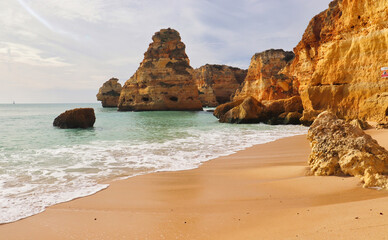 Fototapeta na wymiar Sandy beach with large rocks on a gorgeous winter day in southern Portugal.