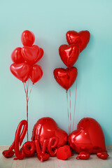 Heart shaped air balloons and gift boxes near blue wall. Valentine's day celebration