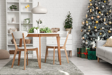 Stylish interior of light living room with mistletoe wreath and burning candles on table
