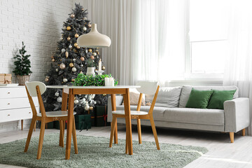 Stylish interior of light living room with mistletoe wreath and burning candles on table