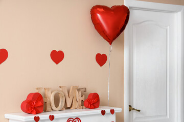 Mantelpiece with decorative word HOME and hearts for Valentine's Day celebration near beige wall