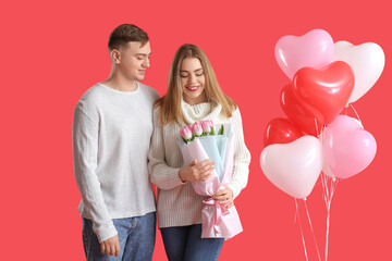 Lovely couple with bouquet of flowers and heart-shaped balloons on red background. Valentine's Day...