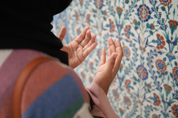 Muslim young woman in hijab is praying in mosque.