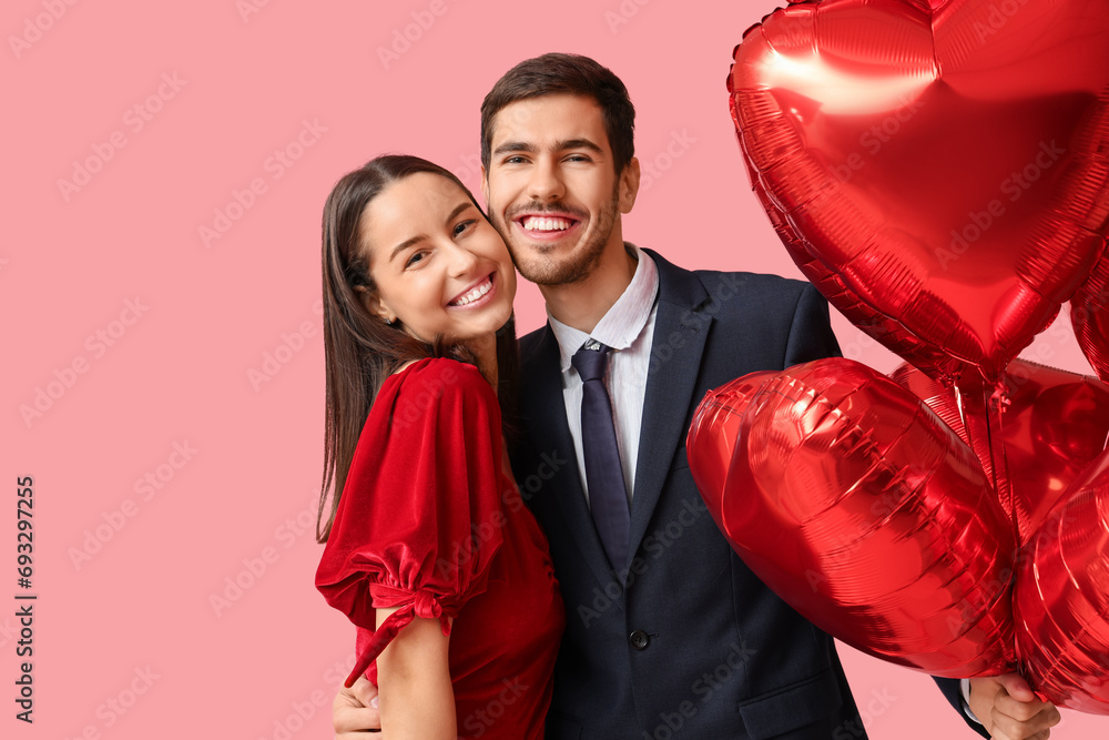 Canvas Prints Beautiful young couple with heart shaped air balloons on pink background. Valentine's day celebration