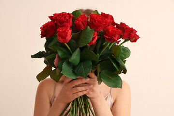 Young woman with bouquet of beautiful red roses on white background. Valentine's day celebration