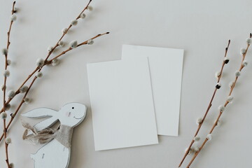 Easter background.Cards mockup, empty blank paper,Easter funny bunny decor ,spring willow branches  in neutral colors on white  background top view flatlay. Copy space.