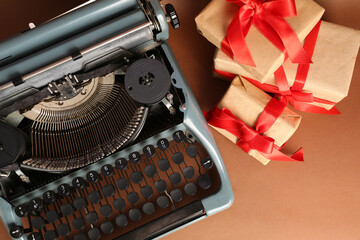 Vintage typewriter with Christmas gifts on brown background