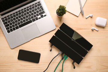Modern wi-fi router with laptop and mobile phone on wooden background - obrazy, fototapety, plakaty