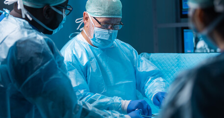 Team of medical doctors performs surgical operation in modern operating room using high-tech...