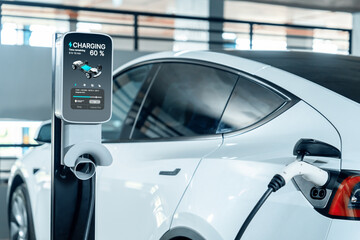 EV electric car recharge at shopping center parking lot charging in downtown city showing urban...