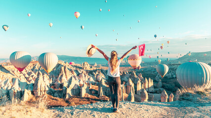Young female tourist looking colorful hot air balloon flying over Cappadocia landscape- Travel,...
