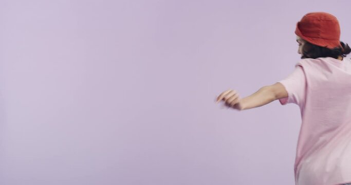 Dancing, smile and young woman in a studio with music, playlist or album for entertainment. Energy, happy and gen z female person from Canada moving to radio or song isolated by purple background.