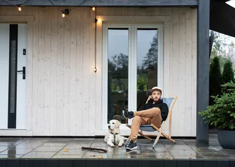 Fotobehang Young man sitting with dog on terrace. © Olena Rudo