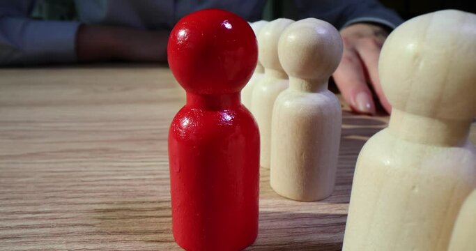 One red leader among similar wooden figurines closeup