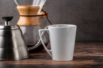 A cup of coffee and third generation pour over coffee brewing equipment on stone floor