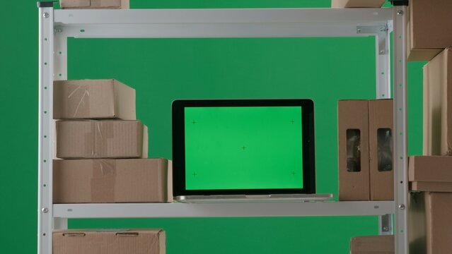 The frame is on a green background. It depicts an empty room with stylings on which stand boxes and a laptop with a green screen. No people in the room. Space for advertising. Medium frame