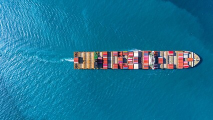 Aerial top view cargo container ship, cargo maritime ship with contrail in the ocean ship carrying container and running at blue sea.