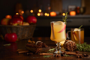 Mulled cider with apples, cinnamon, rosemary, and anise on a background of burning candles.