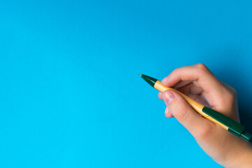 Children hand with pen write on an blue white background. Writing hand.