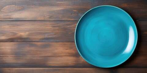 Top view of blue wooden background with empty plate and copy space.