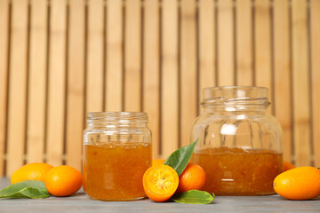 Kumquat and jars of jam on wooden background