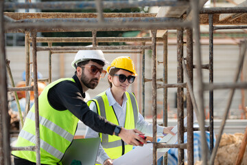 Engineer and architect working on the construction site, double-checking plans and process.