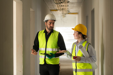 Engineer and architect working on the construction site, double-checking plans and process.